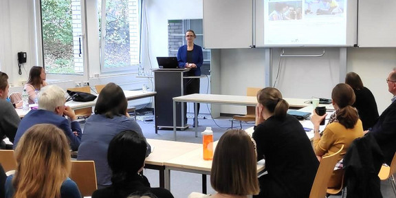 Aileen Edele steht an einem Podium und hält vor einer Gruppe von Menschen ihre Präsentation