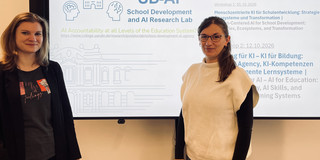 Dr. Manuela Endberg und PD Dr. Ramona Lorenz vor einem Bildschirm mit einer der Titelseite des SD-AI Workshops