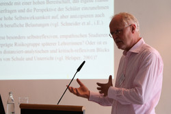 Foto von Prof. Dr. Ewald Terhart bei seinem Vortrag mit einer Präsentationsfolie im Hintergrund