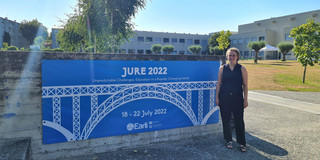 Foto von Katharina Molitor neben einem blauen Banner der JURE 2022