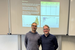 Peter Edelsbrunner und Alexander Naumann lächeln vor der Präsentationsfolie zum Betrachter.