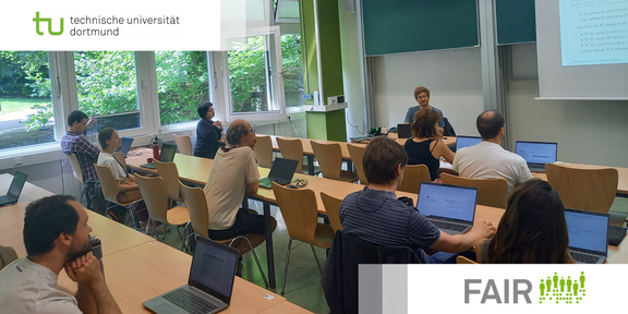 FAIR Workshop Seminarraum mit Personen, die in Tischreihen teilweise an Laptops sitzen, während Dozierender eine Präsentation hält