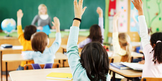 2018-01-29_DFG-Projekt_Nele Sechs Kinder sitzen in ihrem Klassenraum und zeigen auf. Die Lehrerin steht vor den Kindern und unterrichtet sie.