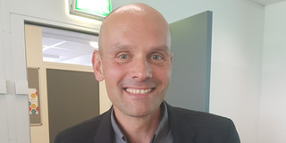 Martin Burghoff steht vor einer Tür im IFS Gebäude