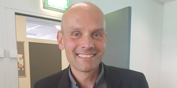 Martin Burghoff steht vor einer Tür im IFS Gebäude
