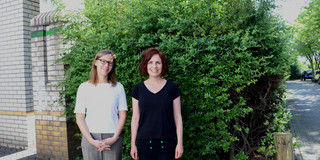 Prof. Dr. Nele McElvany und Kelly Howe stehen vor einem Busch