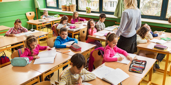 Foto einer Schulklasse, in welcher die Schülerinnen und Schüler Aufgaben bearbeiten