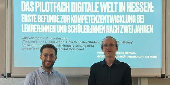 Foto von Prof. Andreas Dengel (links) und Dr. Sebastian Vogel (rechts) vor der Titelfolie seiner Präsentation