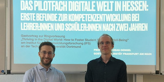 Foto von Prof. Andreas Dengel (links) und Dr. Sebastian Vogel (rechts) vor der Titelfolie seiner Präsentation