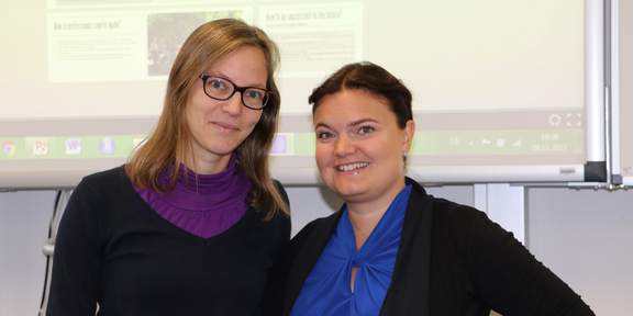 Professorin Nele McElvany und Professorin Heidi Harju-Luukkainen stehen vor einer Präsentation