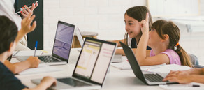 Grundschulkinder arbeiten an Laptops im Klassenraum.