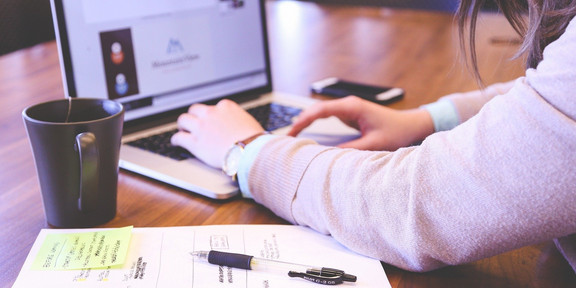 Schülerin sitzt an einem Tisch vor ihrem Laptop