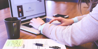 Schülerin sitzt an einem Tisch vor ihrem Laptop