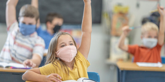 Grundschülerinnen und Grundschüler im Unterricht tragen Atemschutzmasken