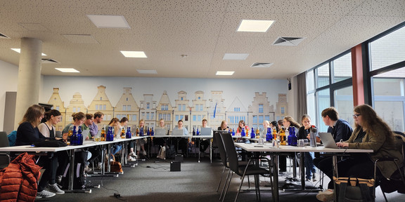 Die Mitglieder der Arbeitsgruppe arbeiten intensiv an Laptops in einem Seminarraum