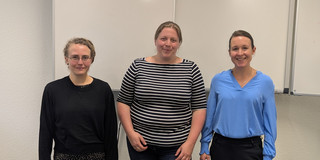 Drei Personen stehen vor einem Whiteboard