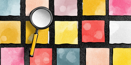 Mehrere Bunte Kacheln mit einem schwarzen Gitter, worüber eine Lupe liegt.