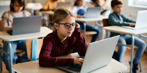 Grundschulkinder arbeiten in ihrem Klassenraum an Laptops