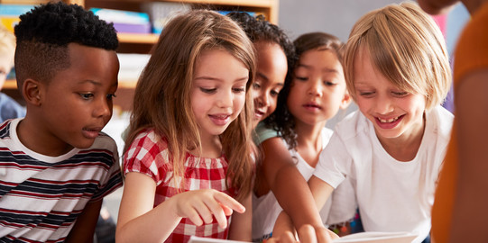 Grundschulkinder schauen sich zusammen ein Buch an 