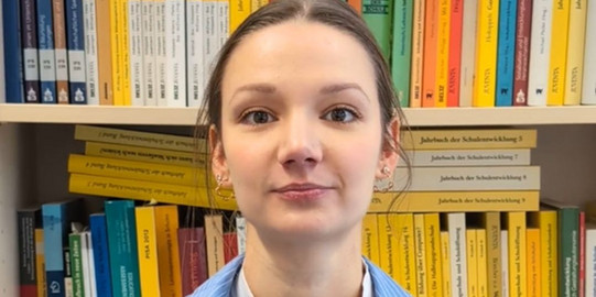 Leonie Dargiewicz steht vor einer Bücherwand im Institut für Schulentwicklungsforschung.