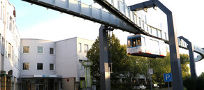 CDI-Gebäude Foto von dem weißen CDI-Gebäude bei Sonnenuntergang mit vorbeifahrender Schwebebahn der TU Dortmund.