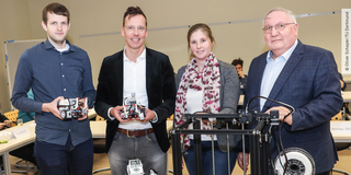 Markus Fleige, Vorsitzender von TECHNIK BEGEISTERT e.V., Prof. Uwe Wilkesmann (zhb), Dr. Annika Ohle-Peters (IFS) und Prof. Winfried Pinninghoff (KARL-KOLLE-Stiftung) mit Lego-Robotern und einem 3D-Drucker, wie sie auch in den Robotik-AGs verwendet werden. 
